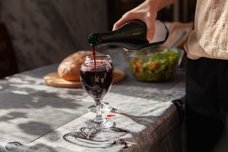 Fles Nero d’Avola met glas wijn en siciliaanse maaltijd
