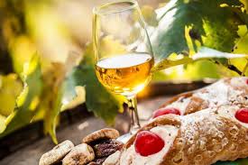 Glas Passito di Pantelleria naast cannoli en amandelen
